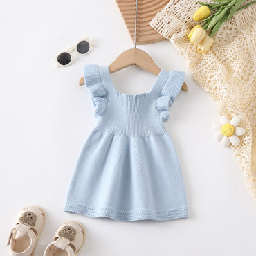 Light blue dress on a hanger with sunglasses, shoes, and flowers on a white background